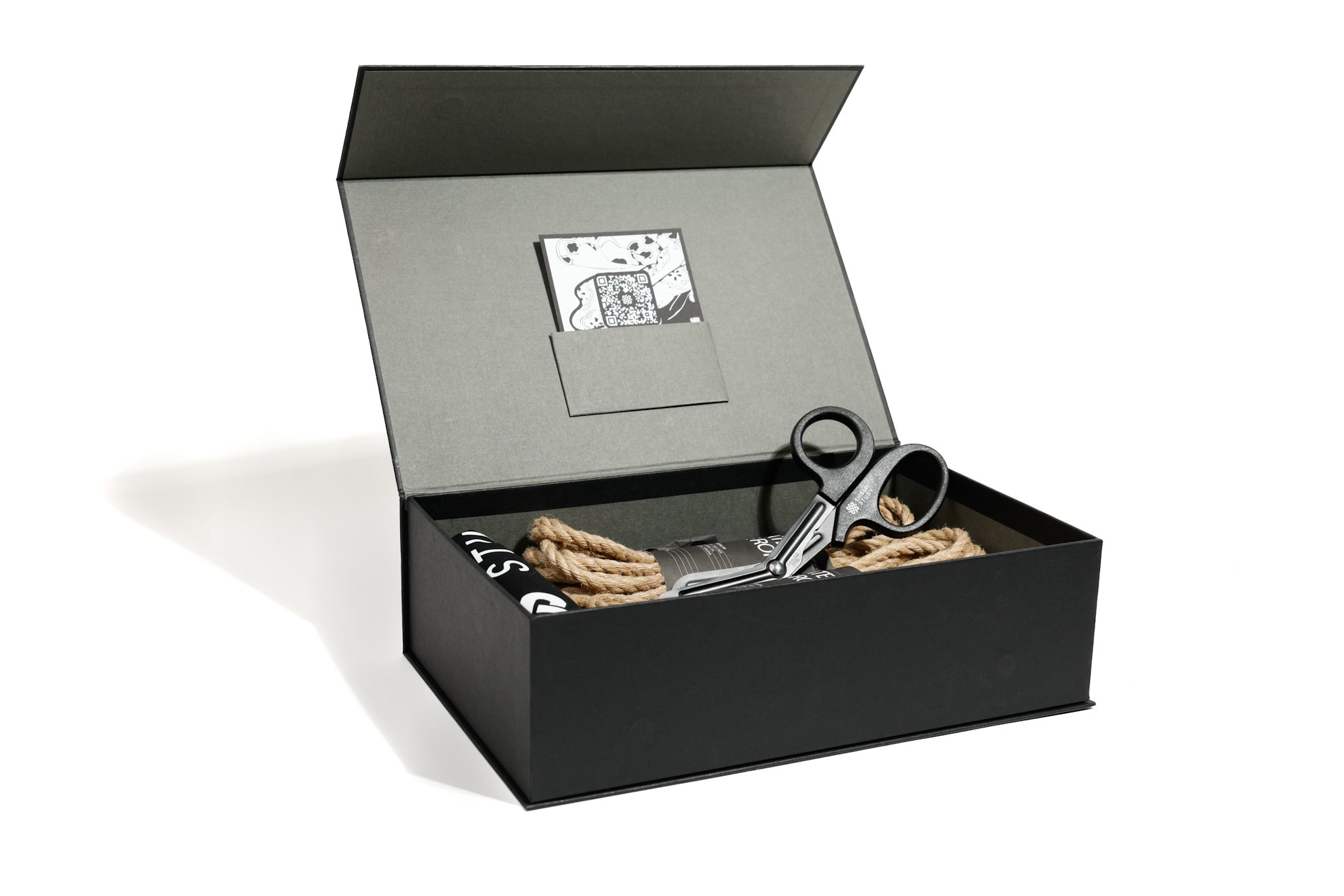 Black gift box with scissors and rope on a white background