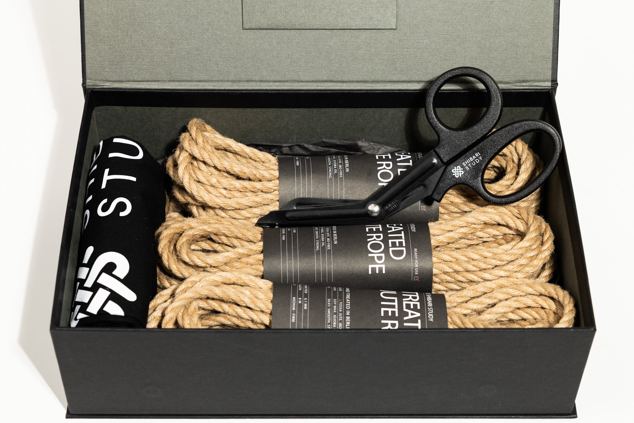 Box containing rope, black shears, and a black and white product packaging.