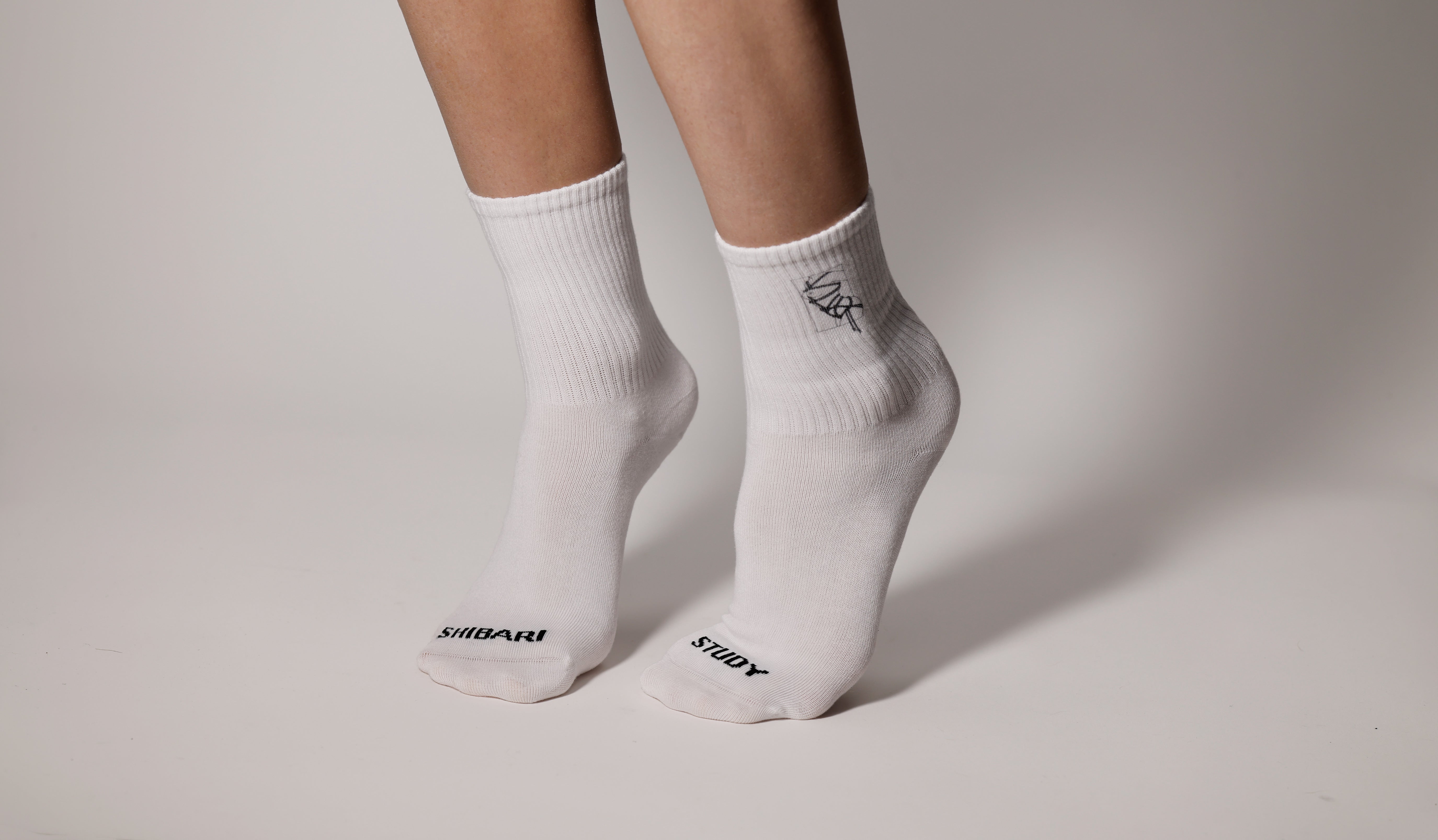 White socks with black Shibari Study branding on a neutral background