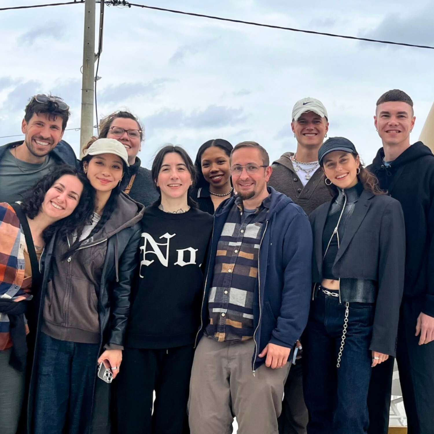 Group of people posing together outdoors with a cloudy sky in the background