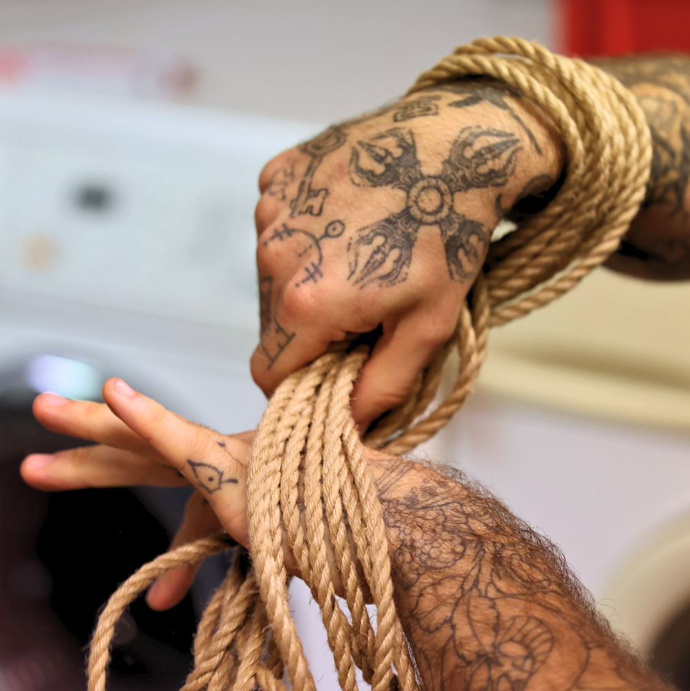 Person with tattoos holding rope against a blurred background